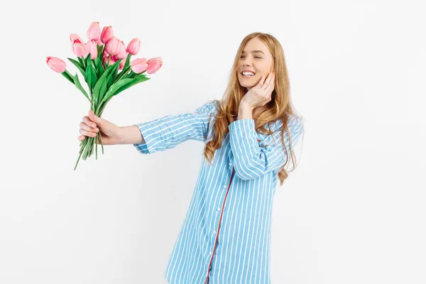 若いです幸せな美しいです女の子でパジャマ保持花束の花ポーズ上の白い背景 — ストック写真