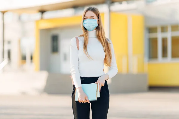 建物の裏にいる少女は コロナウイルス病の蔓延を防ぐフェイスマスクをしています Sars Cov 2に対する彼女の顔に外科マスクを持つ若い女性のクローズアップ — ストック写真