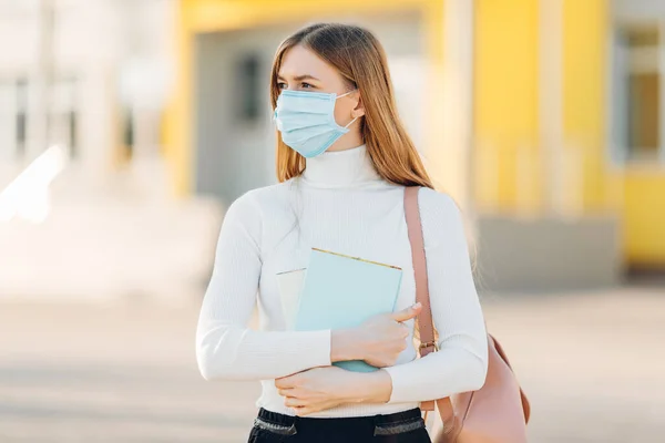 建物の裏にいる少女は コロナウイルス病の蔓延を防ぐフェイスマスクをしています Sars Cov 2に対する彼女の顔に外科マスクを持つ若い女性のクローズアップ — ストック写真