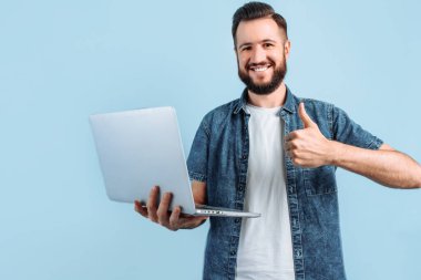 Mutlu, gülümseyen bir adam dizüstü bilgisayarını tutar ve onay verir. Ayrı bir mavi arka planda durarak jesti onaylar.