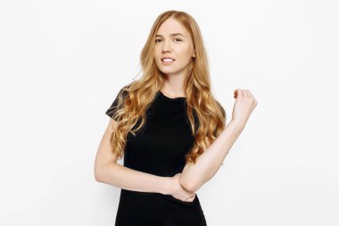 Siyah elbiseli kendinden emin genç bir kadın mutlu bir şekilde kameraya bakıyor. İzole edilmiş beyaz bir arka planda güzel bir kadının stüdyo çekimi.