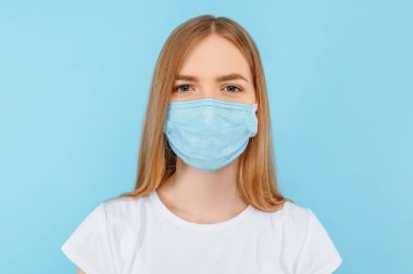 Bulaşıcı hastalıklara karşı koruma, koronavirüs. Genç bir kız enfeksiyonu önlemek için hijyen maskesi takıyor. Solunum hastalıkları. Kapalı Stüdyo çekimi mavi arkaplanda izole edildi