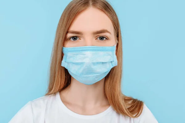 Protection from infectious diseases, coronavirus. A young girl wears a hygiene mask to prevent infection, airborne respiratory disease. closed Studio shot isolated on a blue background