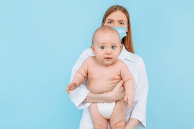 Tıp, sağlık ve pediatri konsepti, dijital kızılötesi termometresi olan kadın bir çocuk doktoru, bebeğin vücut ısısını izole edilmiş mavi bir arka planda ölçer.