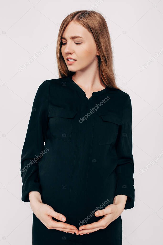 Beautiful pregnant woman in black dress posing on a white background, fashion photography pregnancy