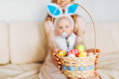 Mutlu Paskalyalar. Paskalya günü tavşan kulaklı bir anne ve küçük bir bebek, Paskalya yumurtası boyalı, eğlen, oyna ve sarıl, kanepede otur. Aile Paskalyayı kutluyor