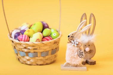 Paskalya yumurtalı Tahta Paskalya Tavşanı, izole edilmiş sarı arka planda. Paskalya dekorasyonu, Paskalya