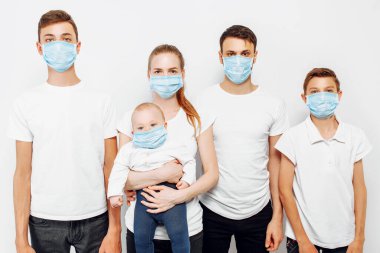 Aile bireyleri ve çocuklar enfeksiyonu önlemek için tıbbi maske takarlar. Solunum hastalıkları, beyaz arka planda izole edilmiş koronavirüs.