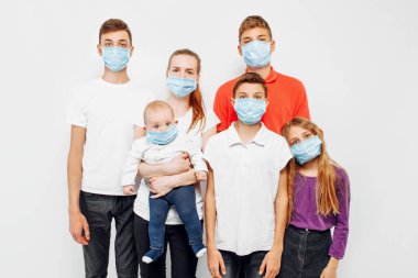 CAVID-19 pandemik koronavirüs. Genç bir aile, ebeveynler ve çocuklar virüslerden korunmak için koruyucu bir maske takıyorlar. Koronavirüs hastalığı.