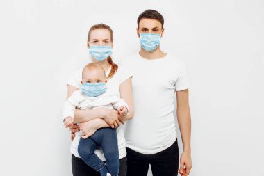 CAVID-19 pandemik koronavirüs. Genç bir aile babası ve kollarında küçük bir çocuk. Virüslerden korunmak için koruyucu bir maske takıyorlar.