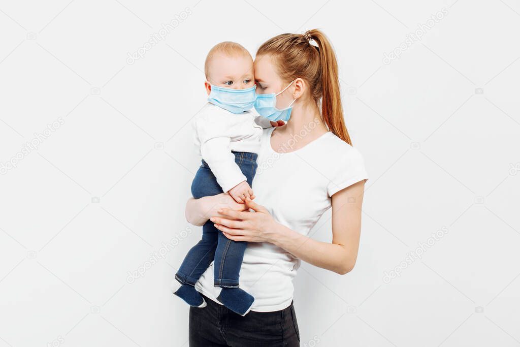 A mother and a small baby in their arms in medical protective masks against viral diseases during the coronavirus epidemic, on a white background