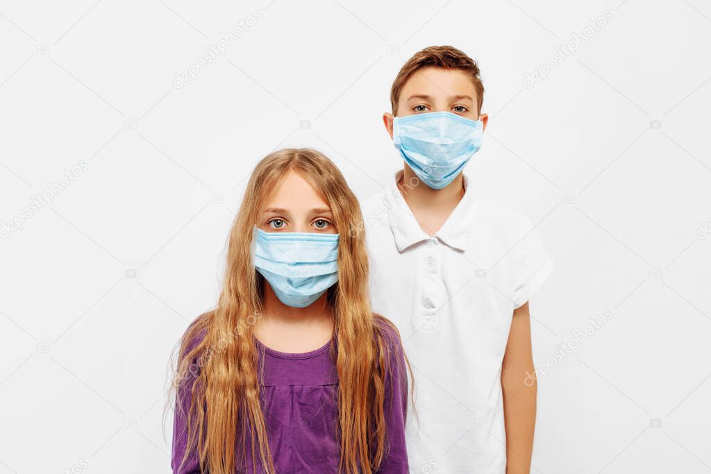 A teenage boy and girl in medical protective masks against viral diseases during the coronavirus epidemic, on a white background