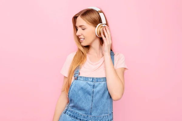 커다란 헤드폰으로 음악을 음악을 즐기고 소녀는 고립된 분홍색 배경을 — 스톡 사진