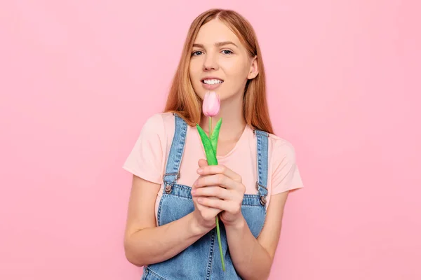 花を持つ繊細な魅力的な若い女の子はピンクの背景に彼女に押されたチューリップを保持しています — ストック写真