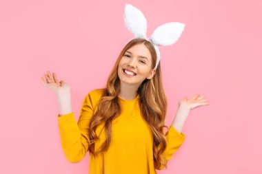 Tavşan ve yumurtaların bayram mevsimi. Paskalya Tavşanı kulaklı mutlu bir kadın pembe arka planda izole edilmiş..