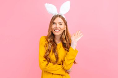 Tavşan ve yumurtaların bayram mevsimi. Paskalya Tavşanı kulaklı mutlu bir kadın pembe arka planda izole edilmiş..