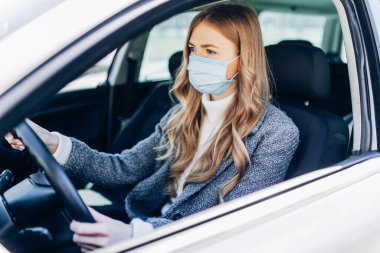 Maskeli güzel bir genç kız arabada oturuyor, Coronavirüs 'e karşı koruyucu maske takıyor, Coronavirus salgını sırasında şehir caddesinde şoför, covid-19.