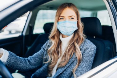 Maskeli güzel bir genç kız arabada oturuyor, Coronavirüs 'e karşı koruyucu maske takıyor, Coronavirus salgını sırasında şehir caddesinde şoför, covid-19.