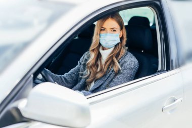 Maskeli güzel bir genç kız arabada oturuyor, Coronavirüs 'e karşı koruyucu maske takıyor, Coronavirus salgını sırasında şehir caddesinde şoför, covid-19.