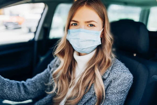 車の中に座ってマスクで美しい若い女の子 コロナウイルスに対する保護マスク コロナウイルス発生中の街の通りのドライバ Covid — ストック写真