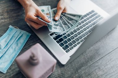 Para sayan ellerin yakın çekimi, dizüstü bilgisayarın arka planında maaş. Uzaktan çalışma, karantina ve koronavirüs kavramı,