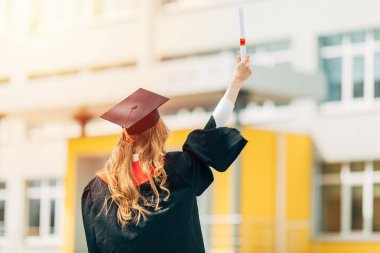 Mezuniyet günü, arka plan, mezuniyet şapkalı ve diplomalı genç bir öğrenci. Başarı kavramı