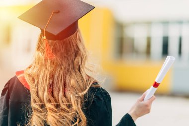 Mezuniyet günü, arka plan, mezuniyet şapkalı ve diplomalı genç bir öğrenci. Başarı kavramı