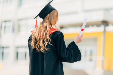 Mezuniyet günü, arka plan, mezuniyet şapkalı ve diplomalı genç bir öğrenci. Başarı kavramı