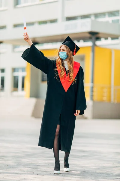 Uczennica Ochronnej Masce Medycznej Czarnej Sukni Dyplomowej Dyplomem Rękach Koncepcja — Zdjęcie stockowe