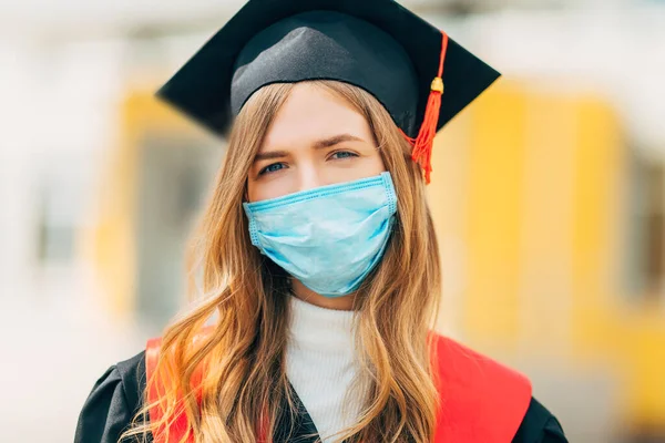 保護医療マスクの女性大学院生黒の卒業式のドレスで 卒業式のコンセプト コロナウイルス — ストック写真