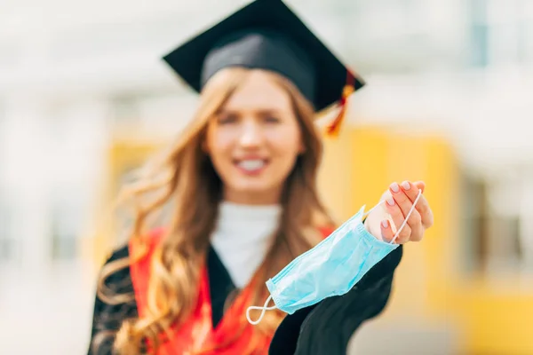 Eine Doktorandin Einem Schwarzen Promotionskleid Eine Medizinische Schutzmaske Der Hand — Stockfoto