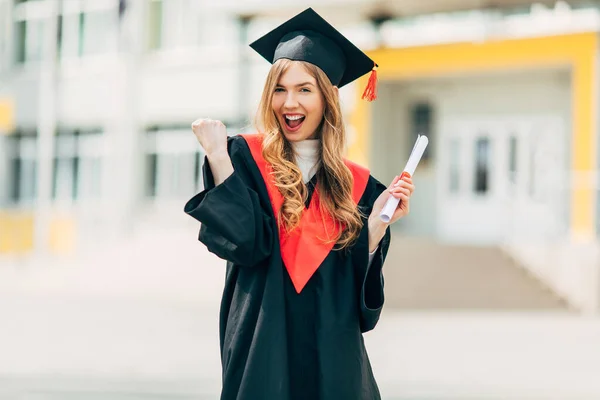 Happy excited beautiful graduate student with a University degree, shows a victory gesture and is happy. Concept of the graduation ceremony