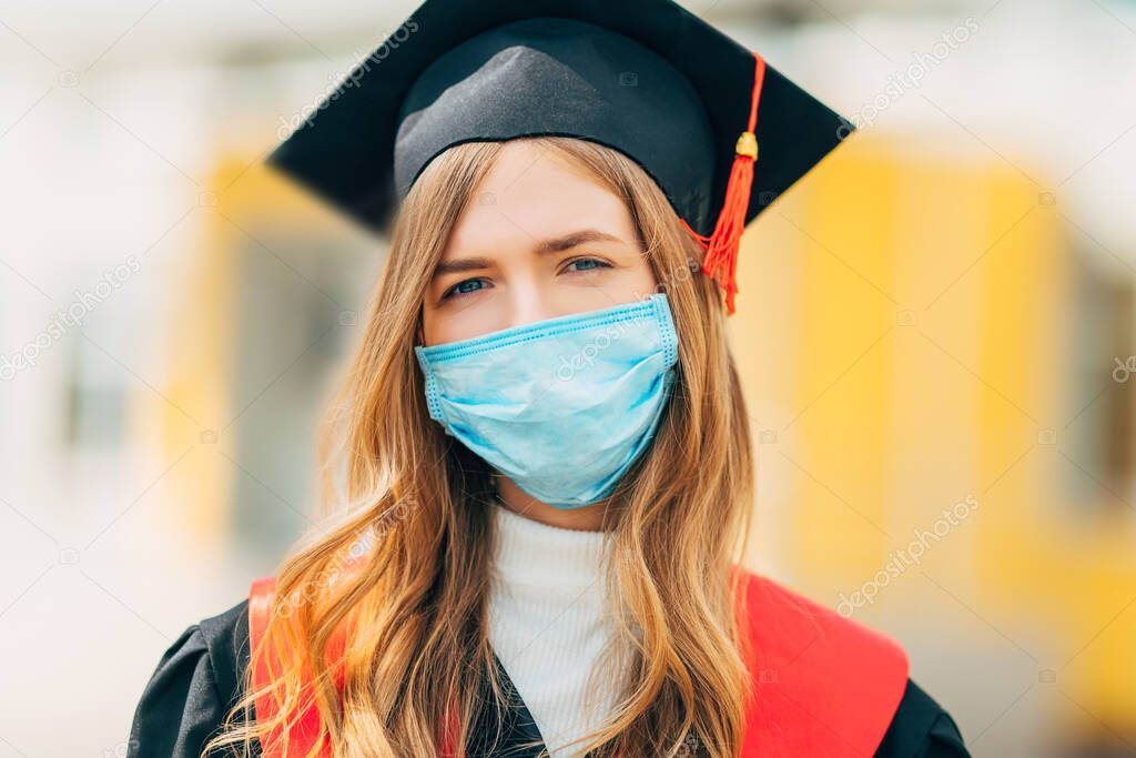 A female graduate student in a protective medical mask, in a black graduation dress. Graduation ceremony concept, quarantine, coronavirus
