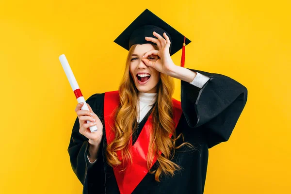 Graduado Atraente Mostra Gesto Pisca Com Diploma Fundo Amarelo Conceito — Fotografia de Stock