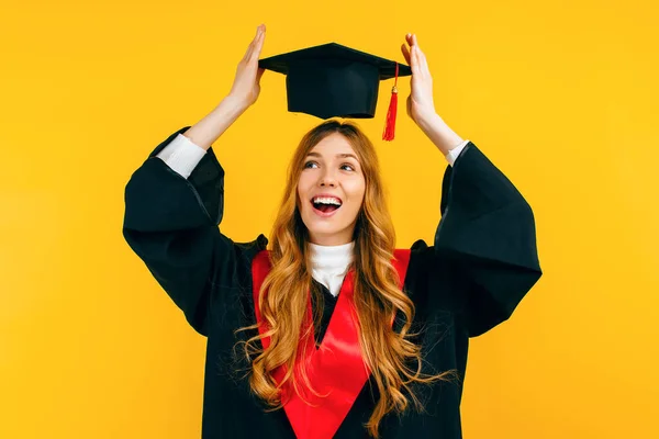 Happy Attractive Graduate Puts Graduation Cap Her Head Isolated Yellow — Stock Photo, Image