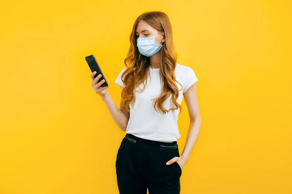 Uma Jovem Mulher Usando Uma Máscara Médica Protetora Usa Telefone — Fotografia de Stock