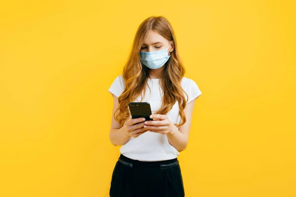 Egy Fiatal Védő Orvosi Maszkot Visel Mobiltelefont Használ Sárga Alapon — Stock Fotó
