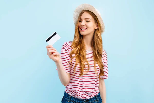 一个戴着夏帽的年轻貌美女子的画像 她带着信用卡 凝视着蓝色背景下的复制空间 — 图库照片