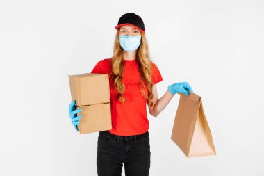 Kurye, beyaz arka planda tıbbi lastik eldivenler ve bir maske içinde karton kutular tutuyor. Hızlı teslimat. Çevrimiçi depolarda karantina, koronavirüs