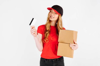 Üniformalı kurye kız elinde karton kutular ve beyaz arka planda bir kredi kartı tutuyor. Teslimat, banka transferi ile ödeme