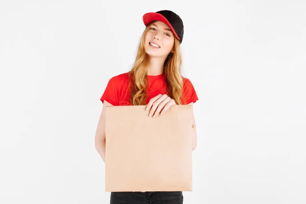 宅配便の制服の少女は 白い背景に食べ物と紙の袋を保持 宅配の概念 オンライン注文 — ストック写真