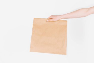 Kurye, izole edilmiş beyaz arka planda içinde yiyecek olan bir kese kağıdı tutuyor. Hızlı ve ücretsiz teslimat. Çevrimiçi mağazalar ve Express dağıtımı