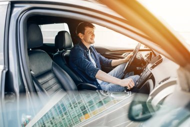 Genç ve mutlu bir adam direksiyondaki sürücü koltuğunda oturuyor.