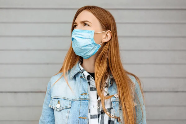 灰色の壁に立っている医療保護マスクの若い女性 隔離コロナウイルス — ストック写真