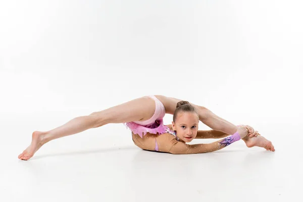 Bir genç Genç kız tek parça streç giysi şovları jimnastik ve beyaz bir arka plan üzerinde bale egzersizleri.