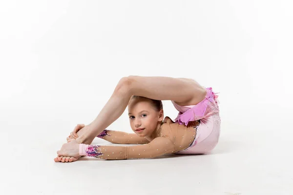 Bir genç Genç kız tek parça streç giysi şovları jimnastik ve beyaz bir arka plan üzerinde bale egzersizleri.