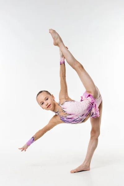 Bir genç Genç kız tek parça streç giysi şovları jimnastik ve beyaz bir arka plan üzerinde bale egzersizleri.