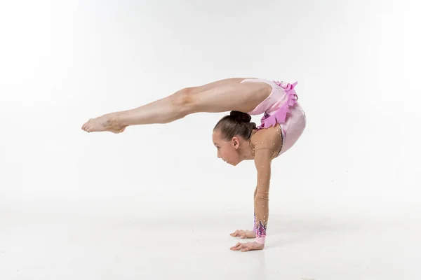 Bir genç Genç kız tek parça streç giysi şovları jimnastik ve beyaz bir arka plan üzerinde bale egzersizleri.
