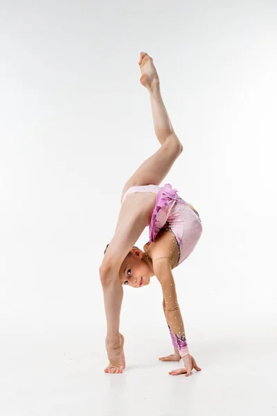 Bir genç Genç kız tek parça streç giysi şovları jimnastik ve beyaz bir arka plan üzerinde bale egzersizleri.