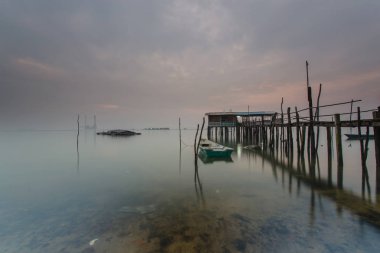Bulutlu uzun pozlama gündoğumu iskeleye vurmuş. Görüntü içeren certai
